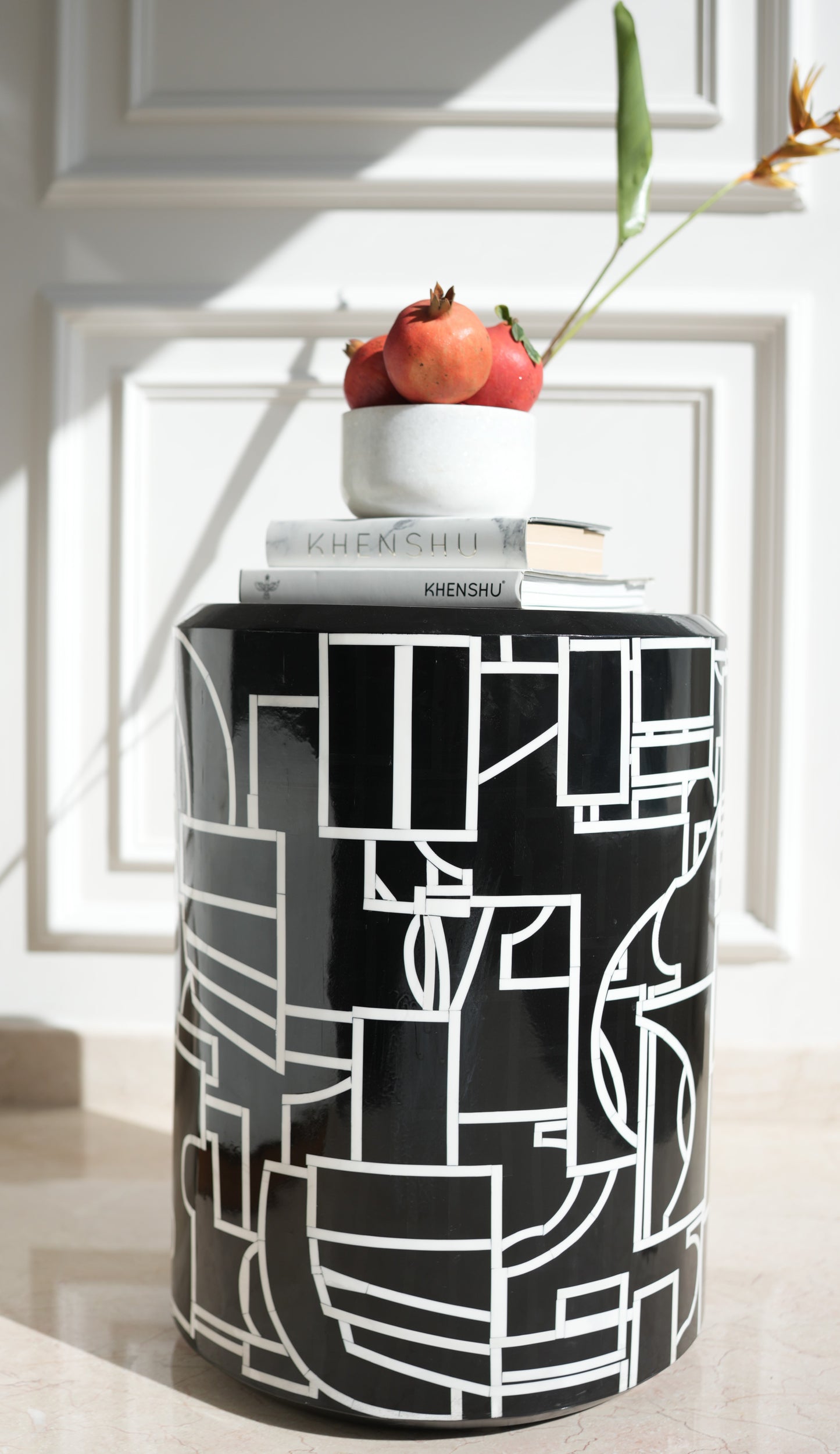 Abstract Picasso side table black cylindrical geometric pattern topped with bowl of pomegranates and books