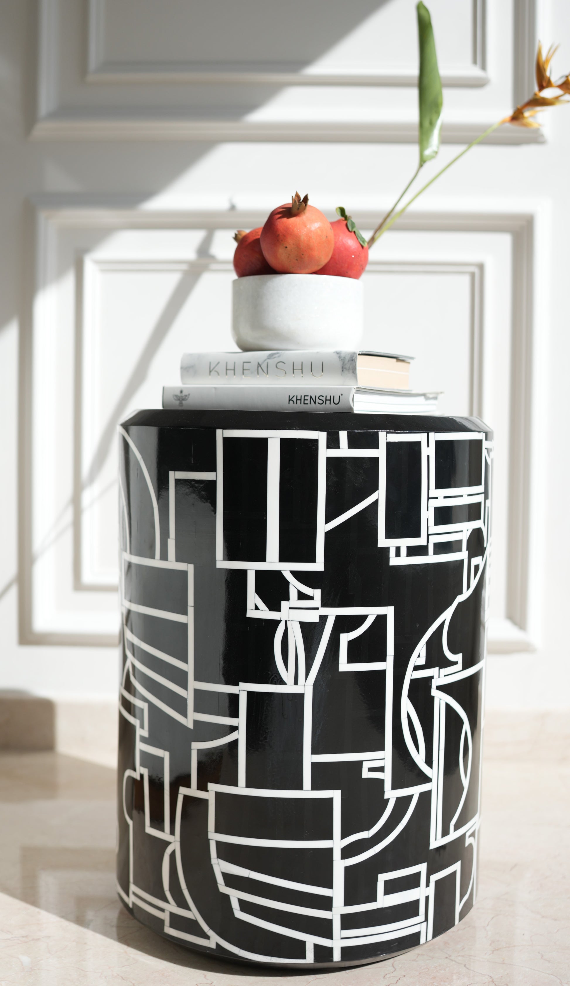 Abstract Picasso side table black cylindrical geometric pattern topped with bowl of pomegranates and books
