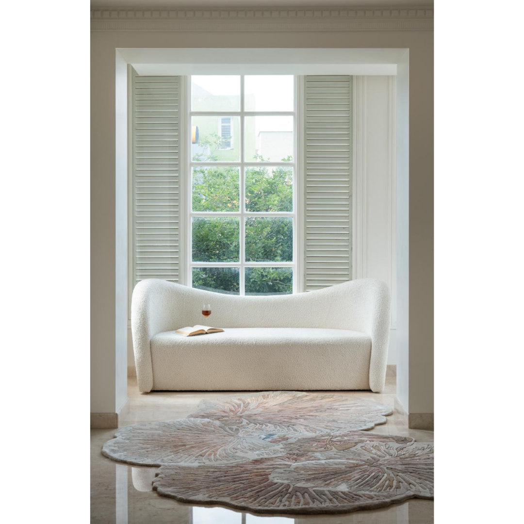 Ivory sofa with curved design placed in a bright room near large window and floral rug