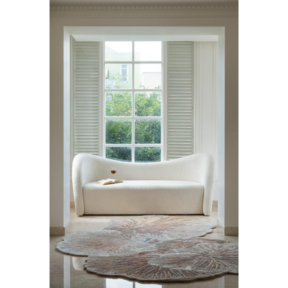 Ivory sofa with curved design placed in a bright room near large window and floral rug