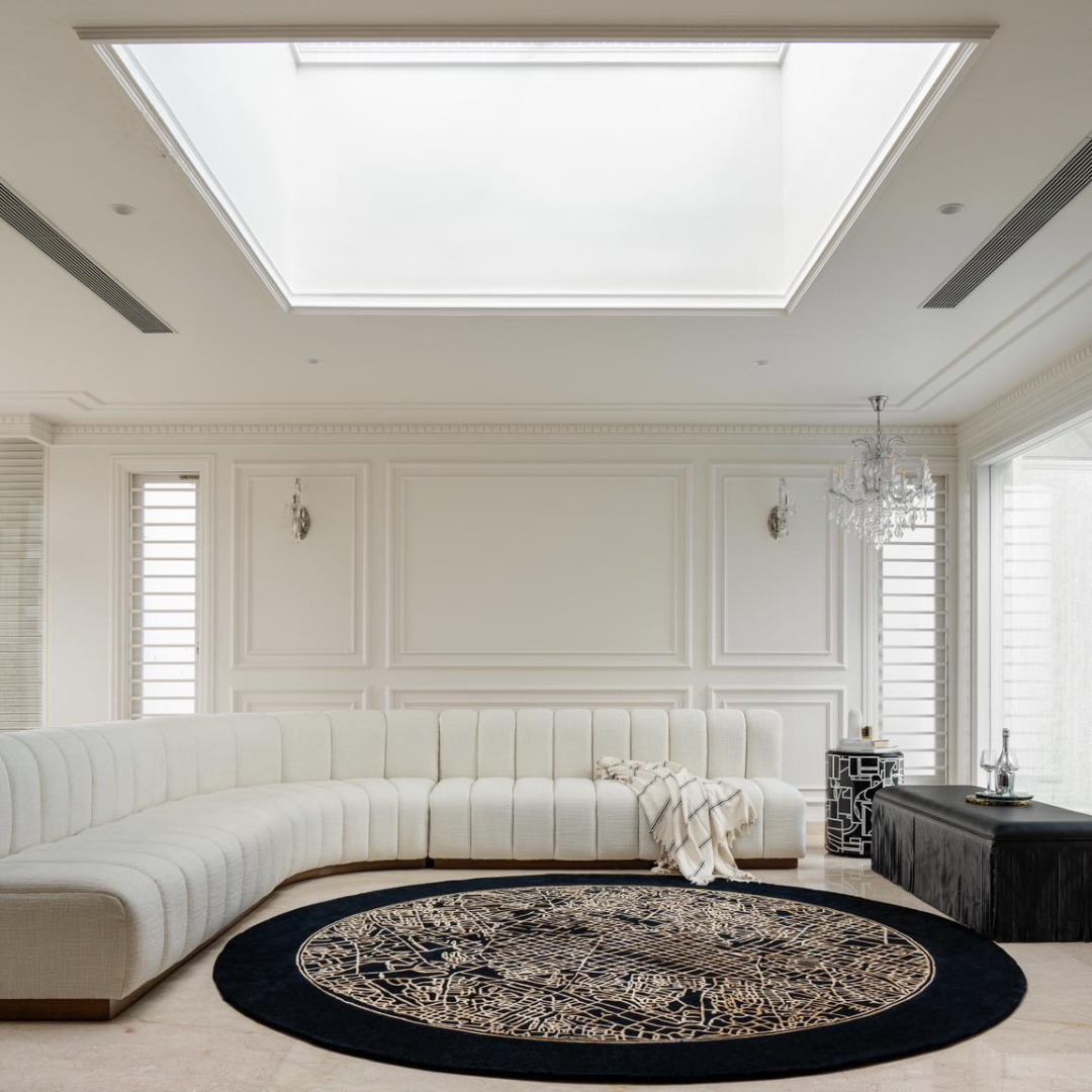 Madrid Rug handcrafted round black rug with intricate gold vine pattern in bright modern living room with curved white sofa