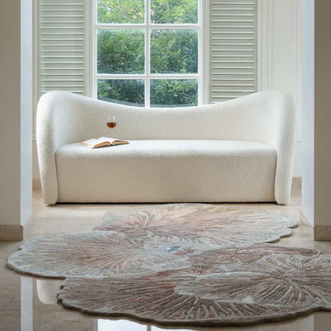 Mushroom Rug in soft earthy tones with scalloped organic shape on marble floor in front of white boucle sofa and window