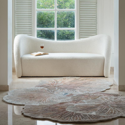 Mushroom Rug in soft earthy tones with scalloped organic shape on marble floor in front of white boucle sofa and window